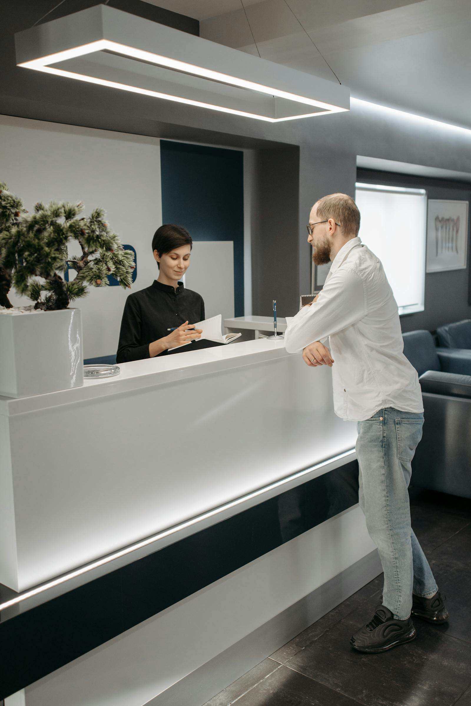 Staff and visitor discussing paperwork at an office reception desk