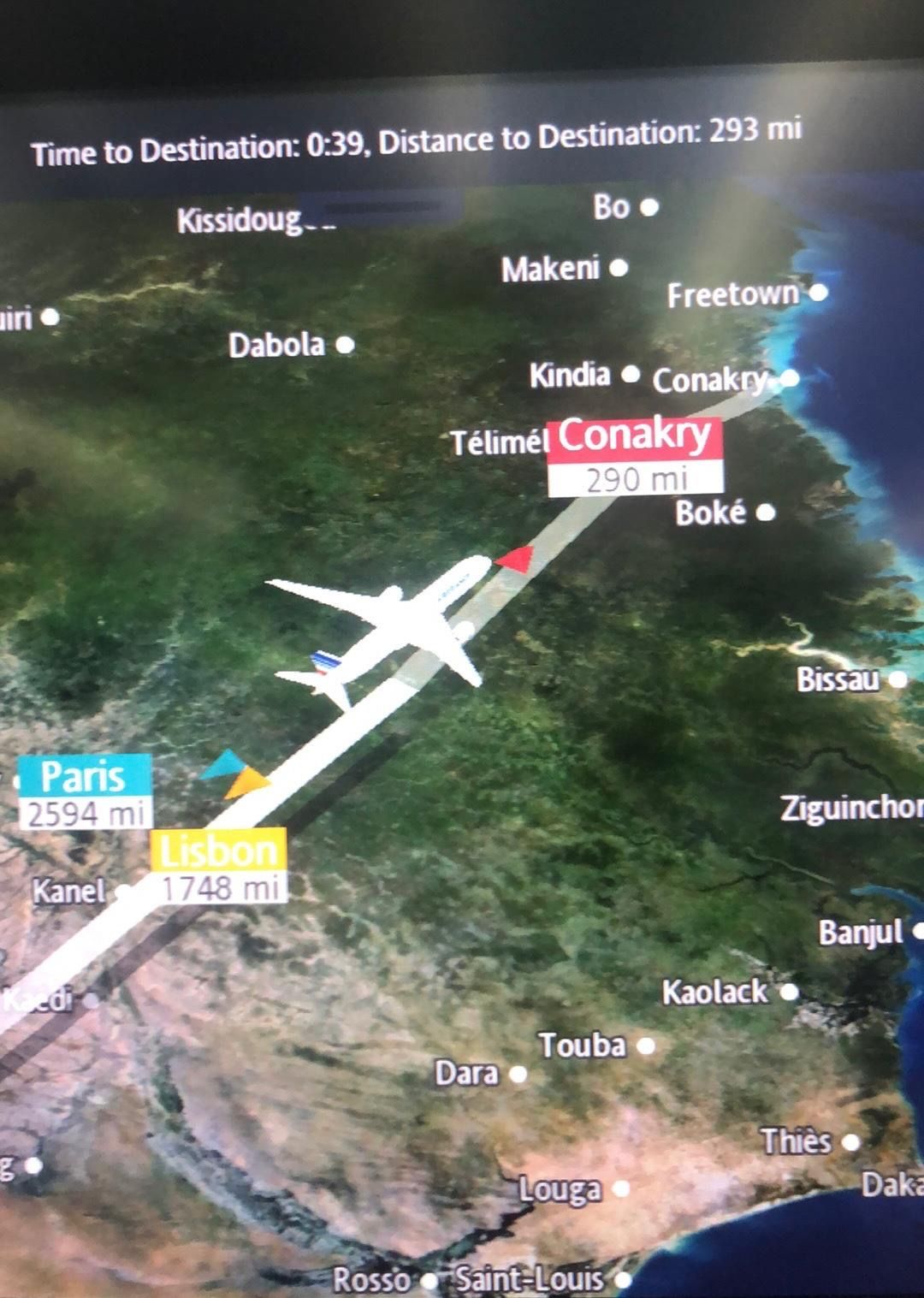 In-flight route map showing the approach to Conakry, Guinea, with distances to Paris and Lisbon.