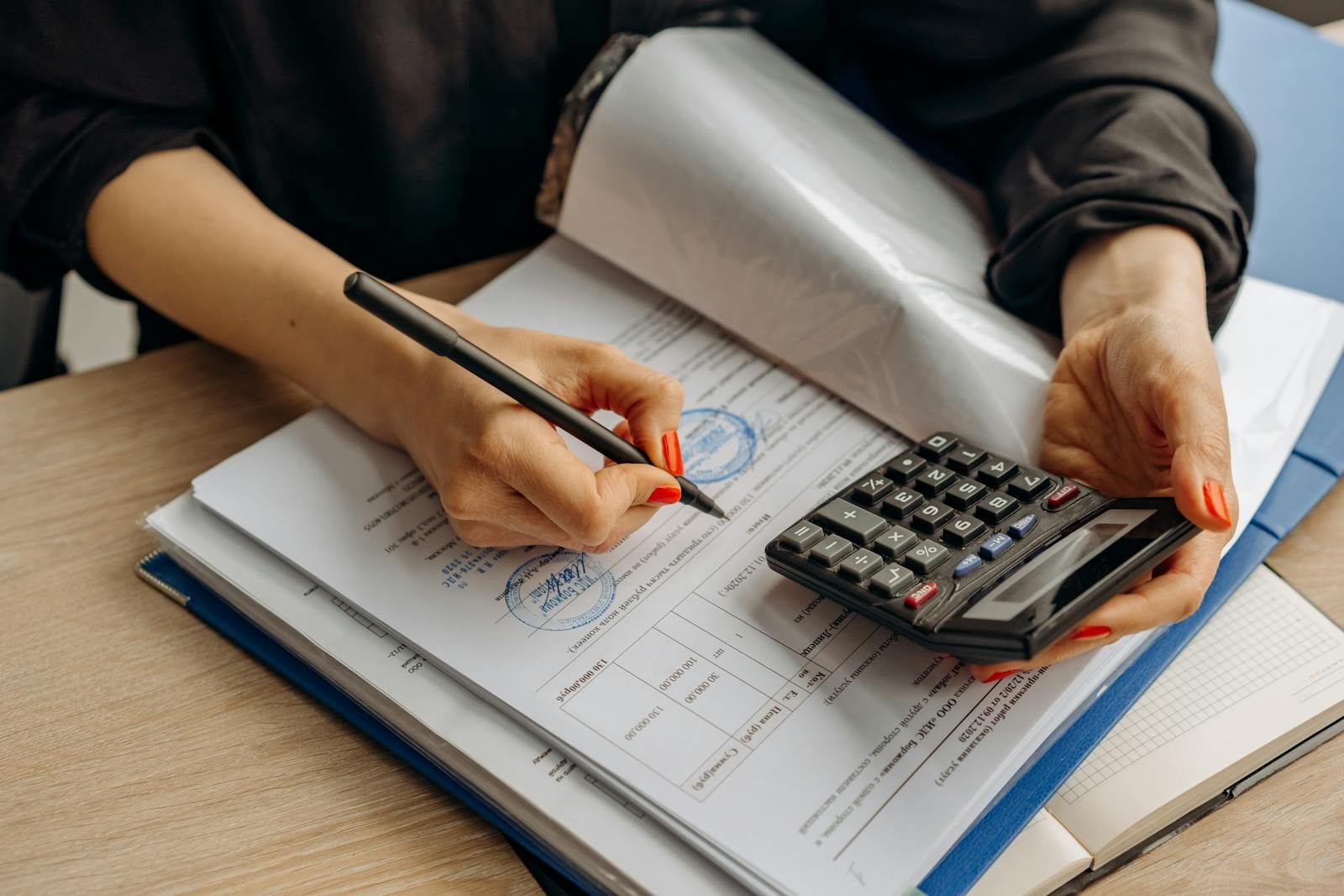 Accountant using a calculator while reviewing bookkeeping paperwork