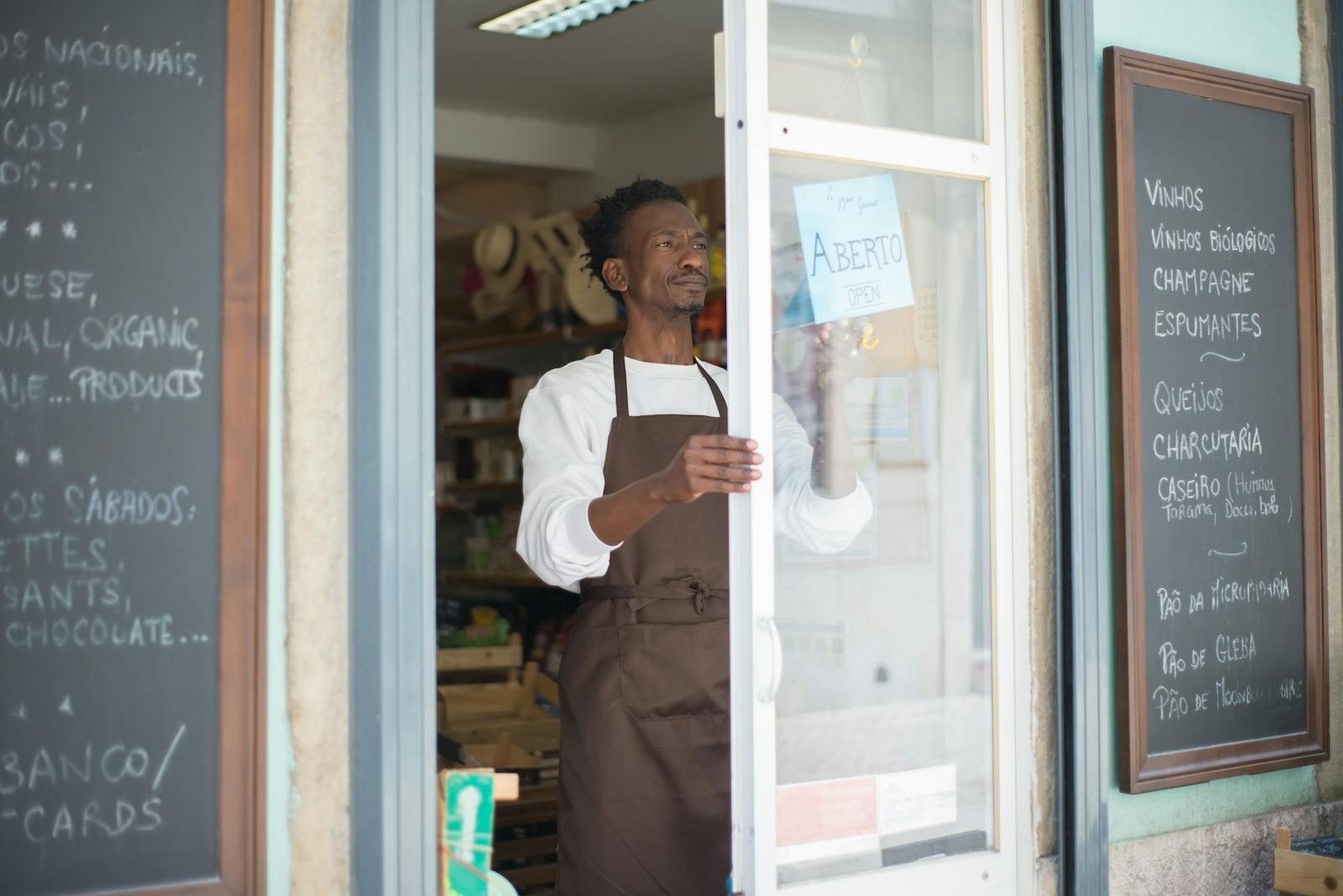 Small business owner in an apron opening the door of his shop, ready for business