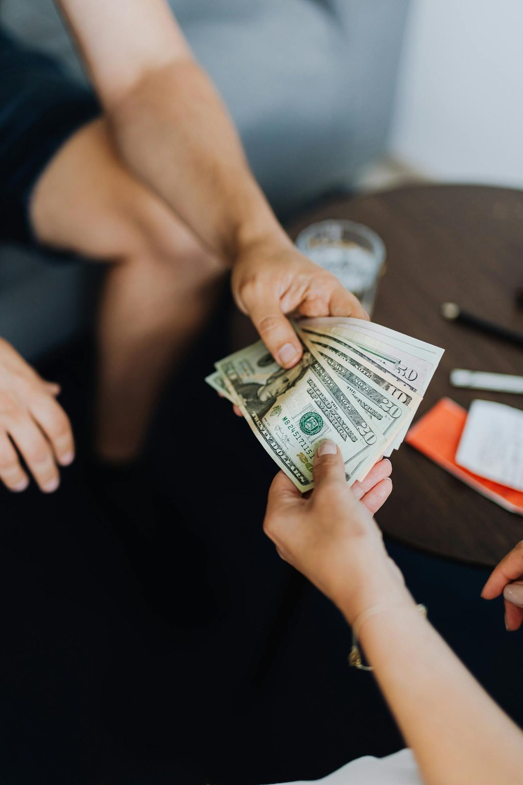 Close-up of hands exchanging US dollar bills indoors