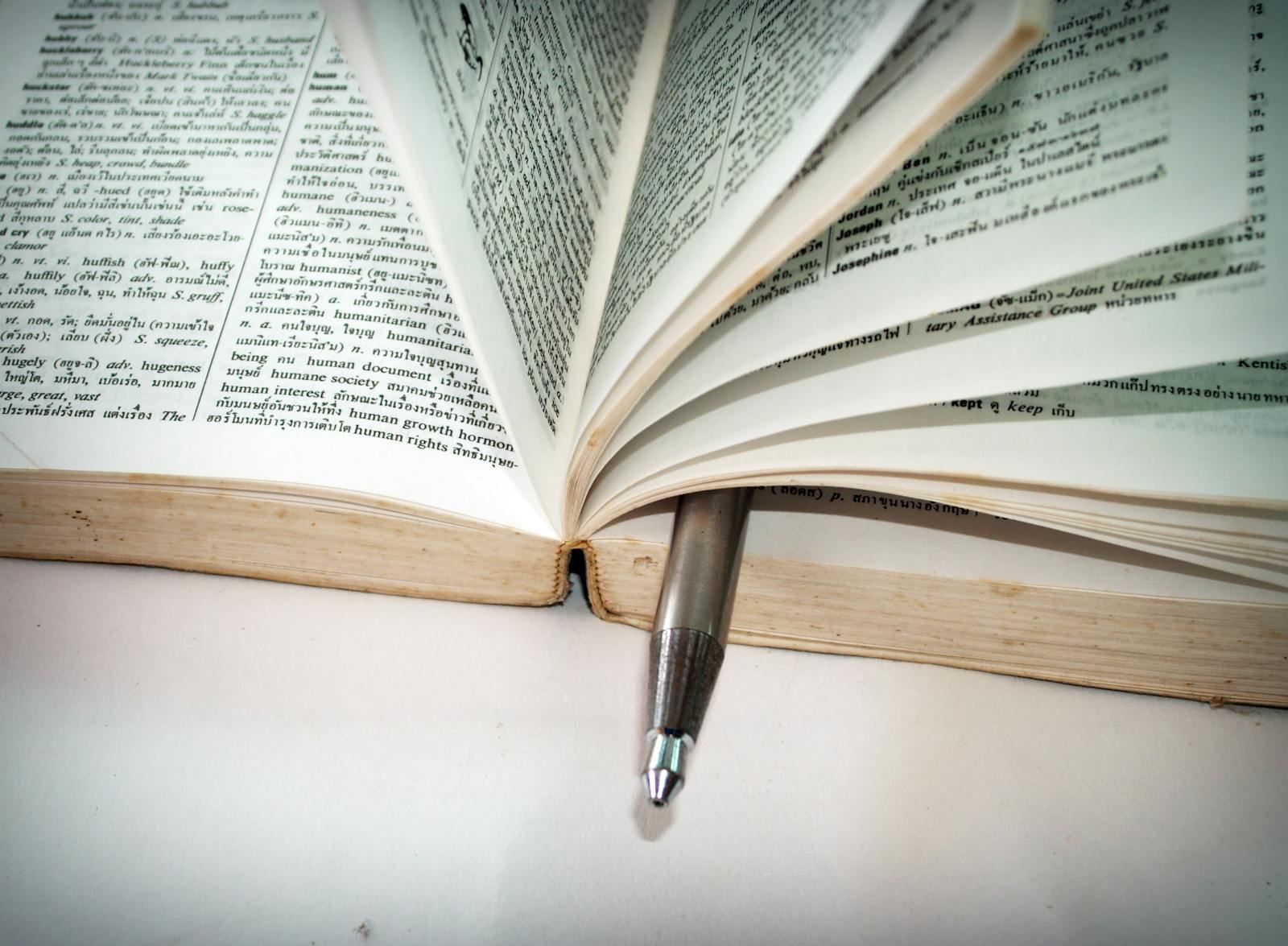 Open dictionary with a pen resting between the pages